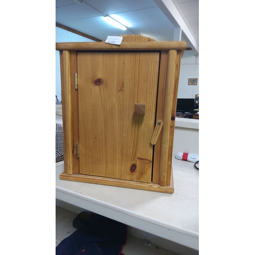 135 - Rustic wooden cabinet with natural finish, featuring a single door, brass hinges, and a simple latch... 