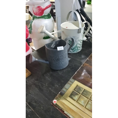 152 - Pair of decorative metal watering cans, featuring ribbed and floral designs.