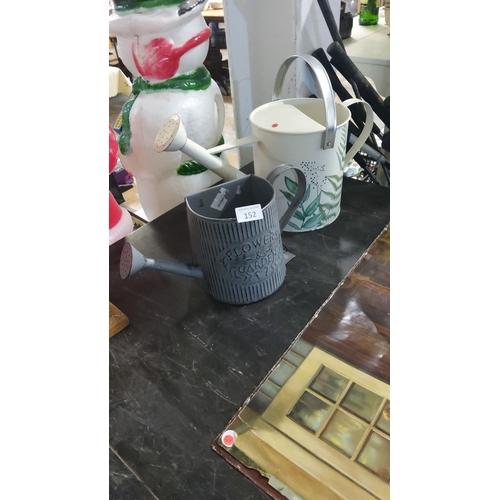 152 - Pair of decorative metal watering cans, featuring ribbed and floral designs.