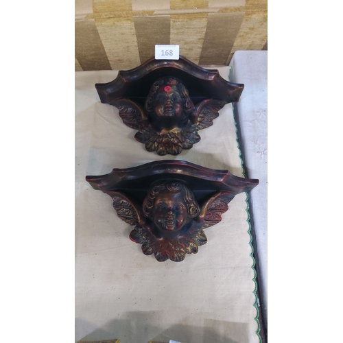 168 - Pair of carved wooden cherub wall brackets, featuring intricate detailing and a dark patina, reminis... 