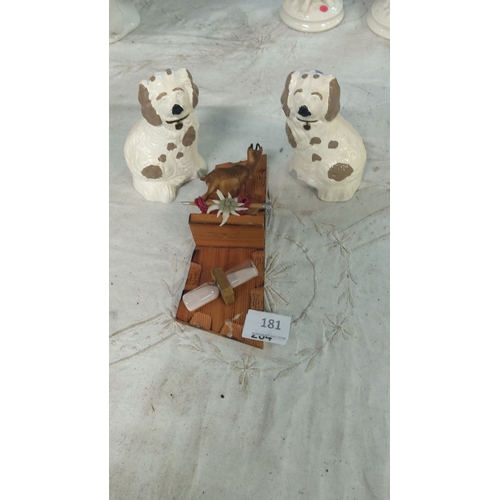 181 - Pair of ceramic dog figurines with painted details, accompanied by a wooden stand featuring a miniat... 