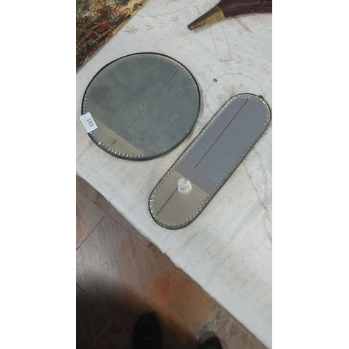 192 - Two vintage beveled edge glass mirrors, one circular and one oval with a handle, featuring a classic... 