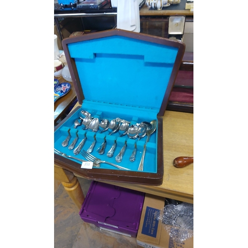 253 - Silver plate part cutlery set in velvet-lined wooden case, featuring ornate handles.