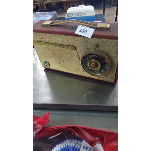 300 - Vintage PYE transistor radio with fabric covering and brass handle, features a classic circular tuni... 