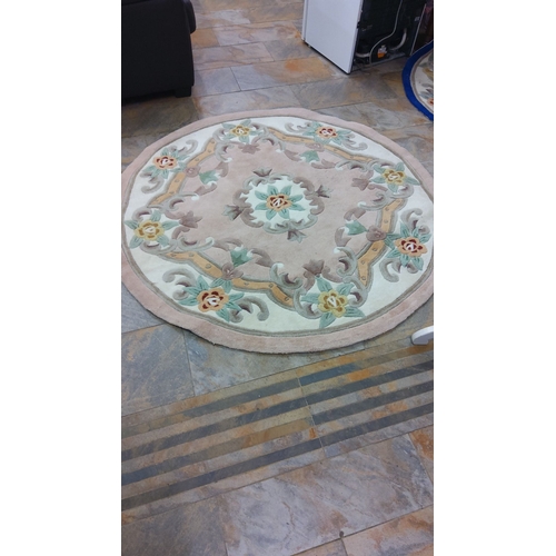 303 - Round wool rug with a floral pattern, featuring muted tones of beige, green, and red. Diameter appro... 