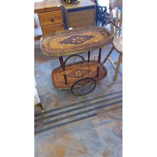 322 - Victorian-style inlaid wooden tea trolley with brass details features intricate floral marquetry and... 