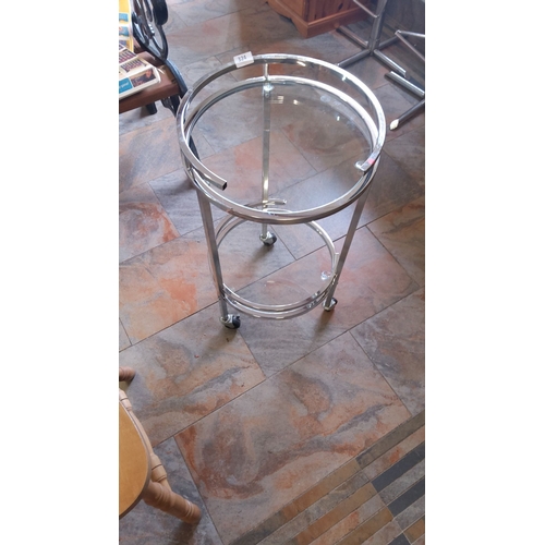 324 - Chrome and glass round cocktail trolley on wheels, featuring a dual-tier design.