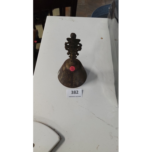 382 - Antique brass servants bell with intricate handle design.