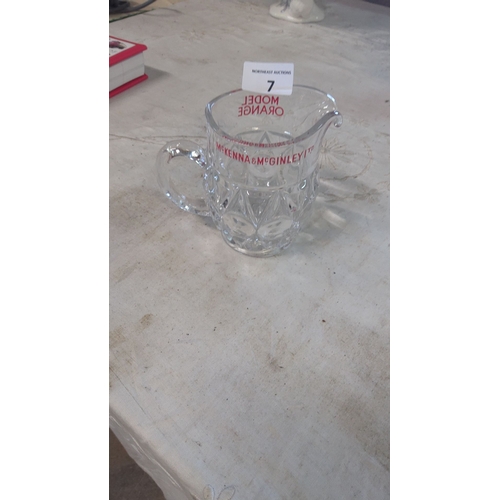 7 - Clear glass pitcher with etched McKenna & McGinley (Model Orange)branding and starburst design, feat... 