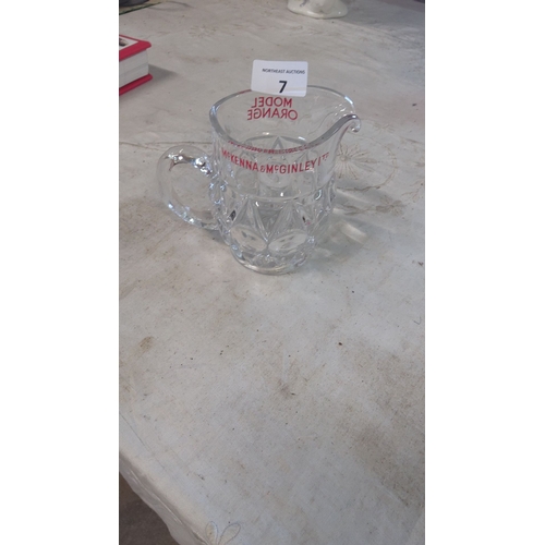 7 - Clear glass pitcher with etched McKenna & McGinley (Model Orange)branding and starburst design, feat... 