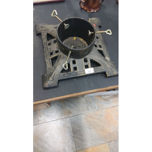 83 - Antique cast iron Christmas tree stand with adjustable screws, featuring a decorative base design.