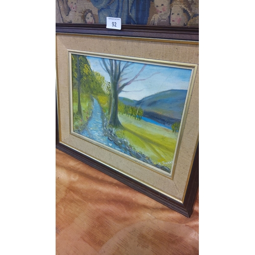 92 - Oil painting depicts a serene landscape with a tree-lined path, lake, and hills. Signed by artist. F... 