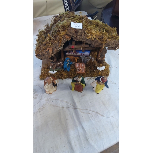 172 - Nativity scene features detailed figures and a rustic stable with a moss roof.