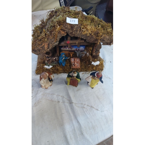 172 - Nativity scene features detailed figures and a rustic stable with a moss roof.