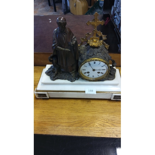 188 - Bronze mantle clock features St Ignatius of Loyola, adorned with a cross and foliage, set on a white... 