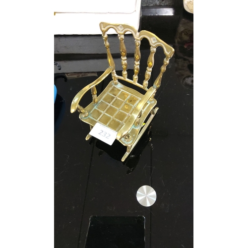 232 - Miniature brass rocking chair with ornate spindle back and grid seat design.