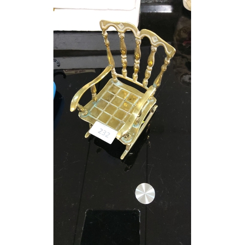 232 - Miniature brass rocking chair with ornate spindle back and grid seat design.