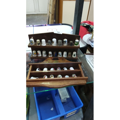 58 - Collection of decorative thimbles with wooden display case, featuring various designs and materials.