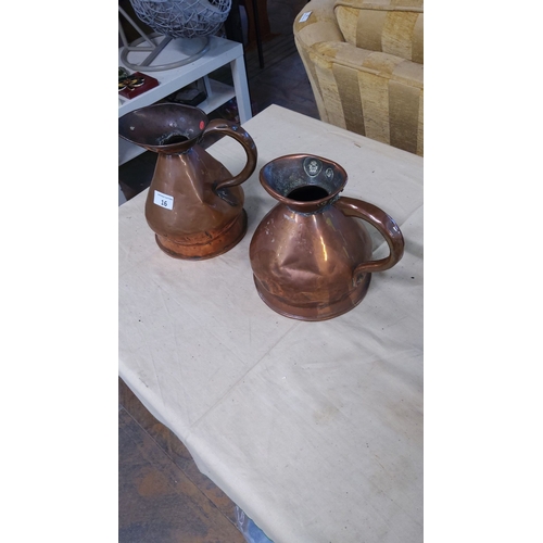 16 - Pair of vintage copper jugs with handle detailing, featuring a unique bulbous shape and wide spouts.