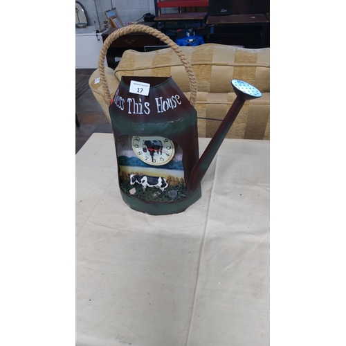 17 - Metal watering can clock with a farm scene, a cow figurine, and a rustic rope handle.