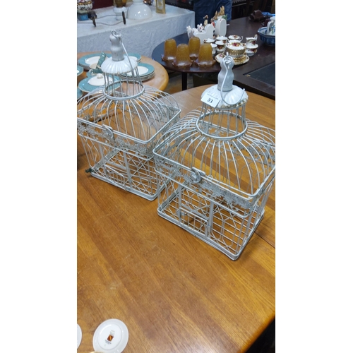 33 - Pair of vintage white-painted metal birdcages with ornate detailing, featuring cloche-style tops and... 