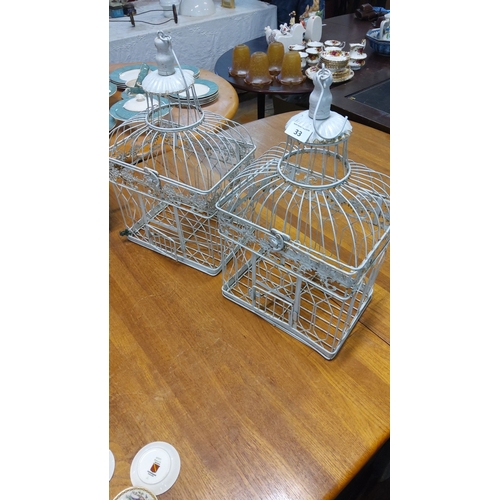 33 - Pair of vintage white-painted metal birdcages with ornate detailing, featuring cloche-style tops and... 