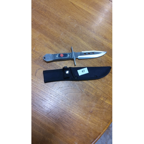 47 - Knife with stainless steel blade, serrated spine, and composite handle. Includes black sheath.