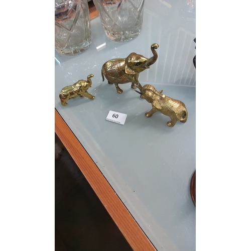 60 - Set of three brass elephant figurines, intricately detailed with etched patterns.