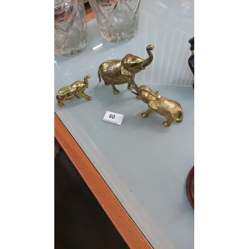 60 - Set of three brass elephant figurines, intricately detailed with etched patterns.