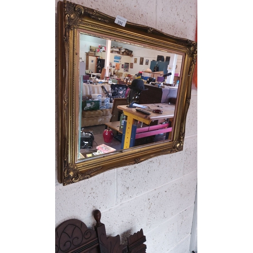 394 - Ornate vintage mirror with a gilded frame featuring intricate detailing.