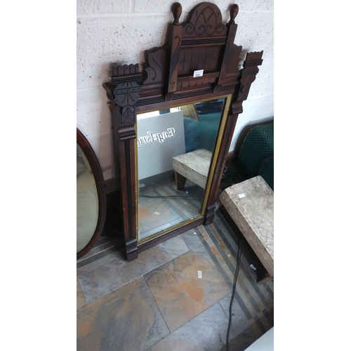 395 - Victorian-style wooden mirror with intricate cresting, featuring dark wood tones and decorative arch... 