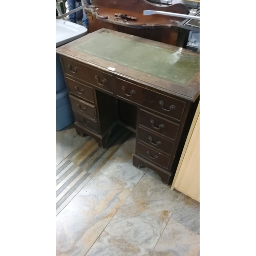 472 - Mahogany kneehole desk with dark leather inlay, brass handles, and eight drawers. Features classic e... 