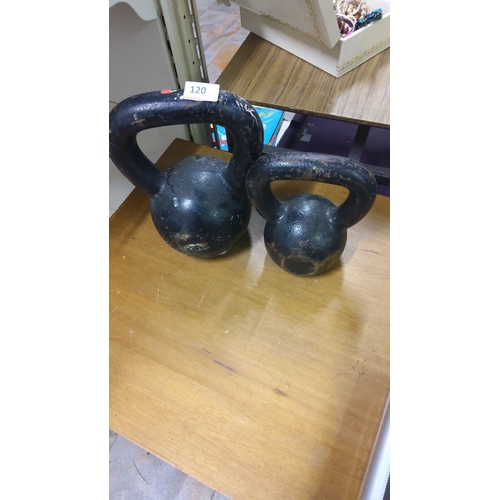 120 - Pair of vintage cast iron kettlebells with a worn black finish. Weight markings are visible.