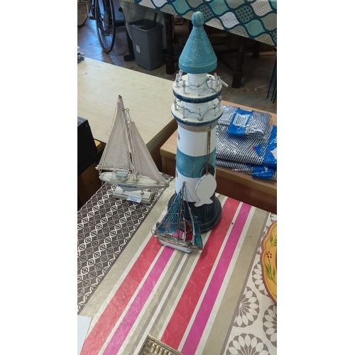 198 - Decorative nautical-themed items include a painted wooden lighthouse and two intricate sailboat figu... 