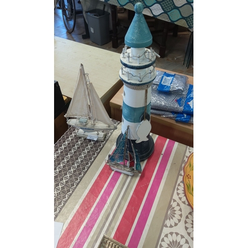 198 - Decorative nautical-themed items include a painted wooden lighthouse and two intricate sailboat figu... 