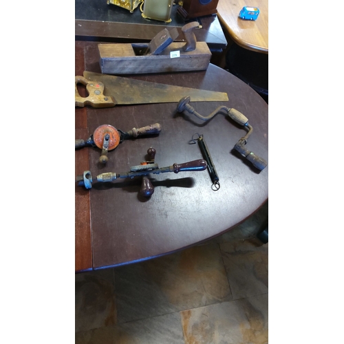 279 - Mixed vintage woodworking tools including a hand saw, wooden plane, braces, and drills.