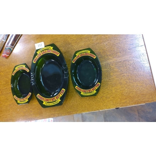 112 - Set of three vintage green glass ashtrays branded with John Smith's Bitter. Features bold yellow and... 