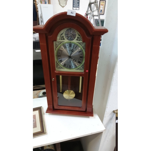 41 - Wooden mantel clock with Roman numerals, brass pendulum, and decorative detailing.