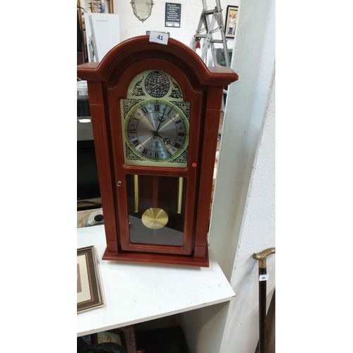 41 - Wooden mantel clock with Roman numerals, brass pendulum, and decorative detailing.