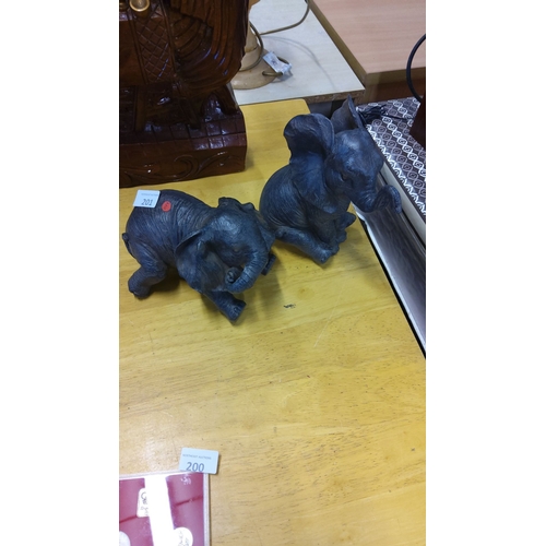 201 - Pair of heavy resin elephant figurines with textured detailing, depicting playful poses.