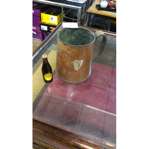 242 - Antique leather Guinness tankard features a harp emblem and exhibits a rich patina. It includes a mi... 