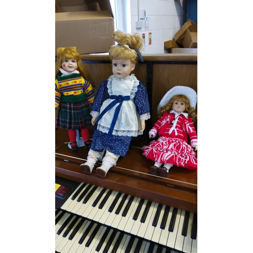 320 - Three vintage porcelain dolls, each dressed in detailed period-inspired outfits. Includes a large bl... 