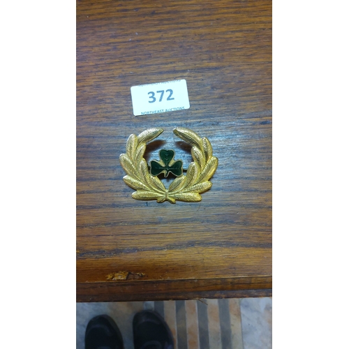 372 - Gold-tone military or aviation cap badge featuring a laurel wreath and enamel green shamrock. The de... 