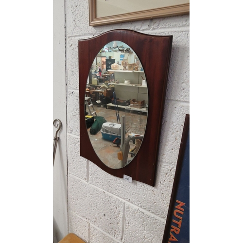 409 - Vintage wall mirror with an oval glass set in a mahogany-veneered shield-shaped frame.