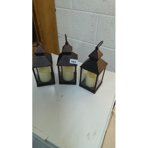 433 - Set of three vintage-style metal and glass lanterns with pillar candles feature a rustic black and c... 