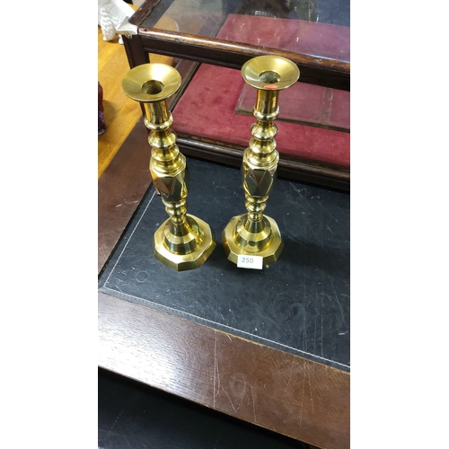 250 - Pair of solid brass candlesticks with elegant turned detailing and octagonal bases. Classic design.