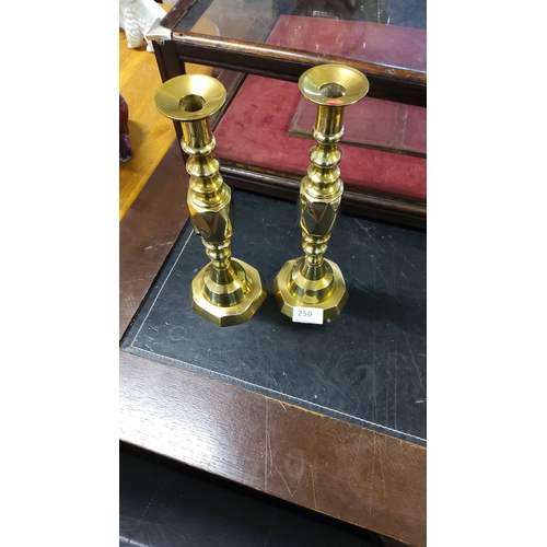 250 - Pair of solid brass candlesticks with elegant turned detailing and octagonal bases. Classic design.