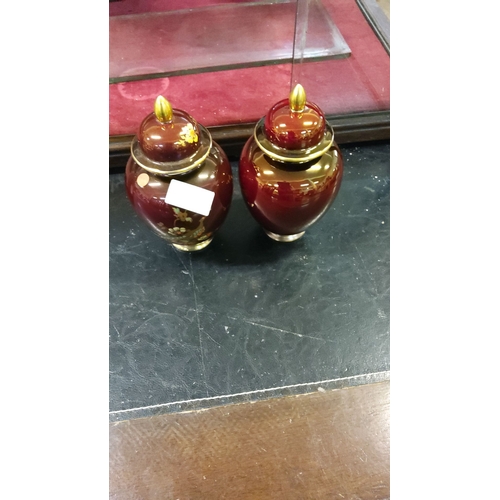 253 - Pair of Carlton Ware lidded ginger jars in deep burgundy glaze with gilded accents, featuring floral... 