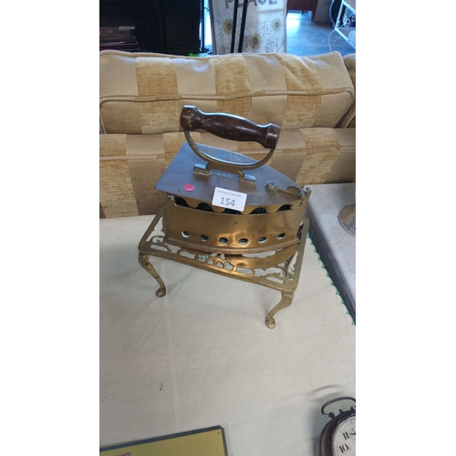 154 - Antique brass charcoal iron with wooden handle, resting on an ornate brass trivet.