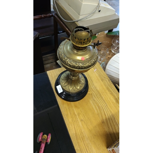 181 - Brass oil lamp base with ornate embossed detailing, fluted pedestal base, and black circular foot.